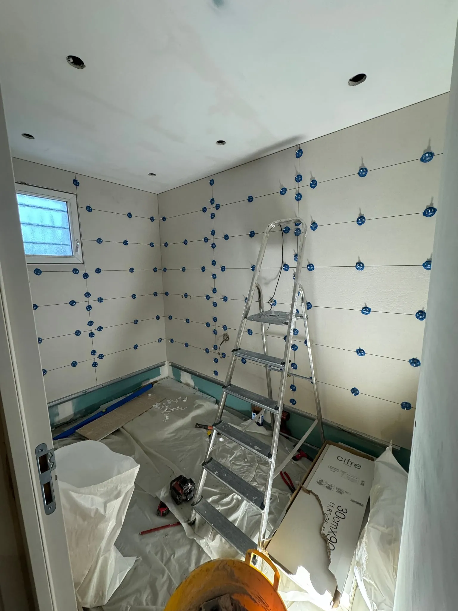 Pose de la faïence murale en cours dans la salle de bain