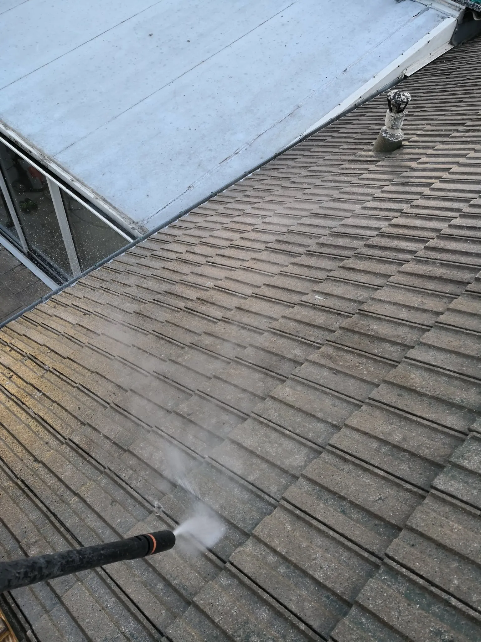 Démoussage au nettoyeur haute pression autour d'une fenêtre de toit